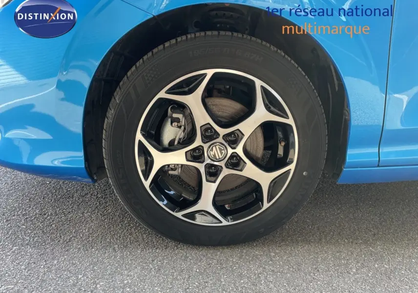 Gros plan sur la roue avant gauche d'une MG3 2024 bleu Como Metal avec jante alliage bicolore et logo MG central.