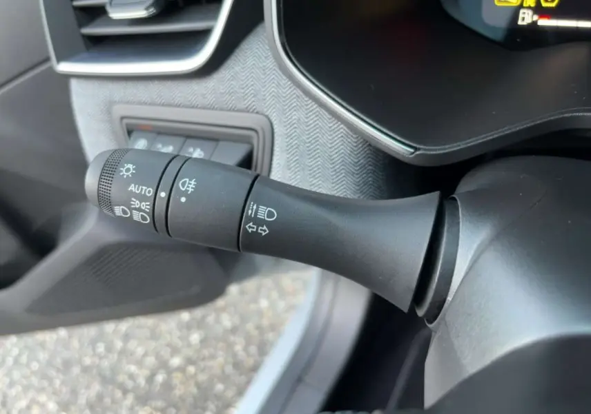 Gros plan sur la commande des feux et clignotants à gauche du volant dans l’habitacle de la Renault Clio gris rafale.