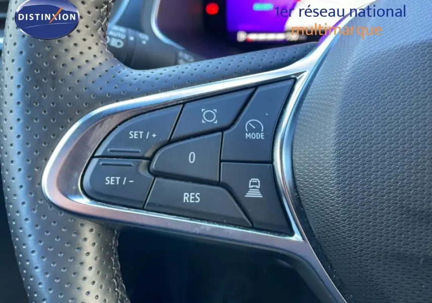 Gros plan sur les commandes au volant en cuir perforé noir du Renault Symbioz 2025, avec écran numérique flou en arrière-plan.