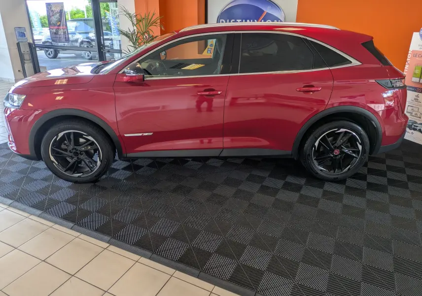 Vue de profil côté gauche d’un DS7 rouge 2019 avec attelage, soulignant ses jantes noires et son design élégant.