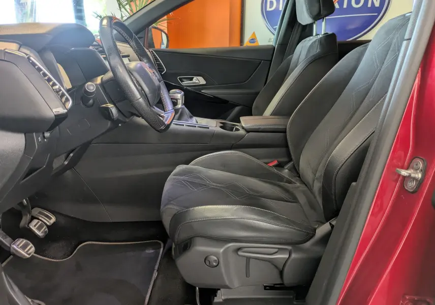 Vue intérieure côté conducteur du DS7 rouge 2019, montrant sièges en cuir noirs et volant avec boîte manuelle.