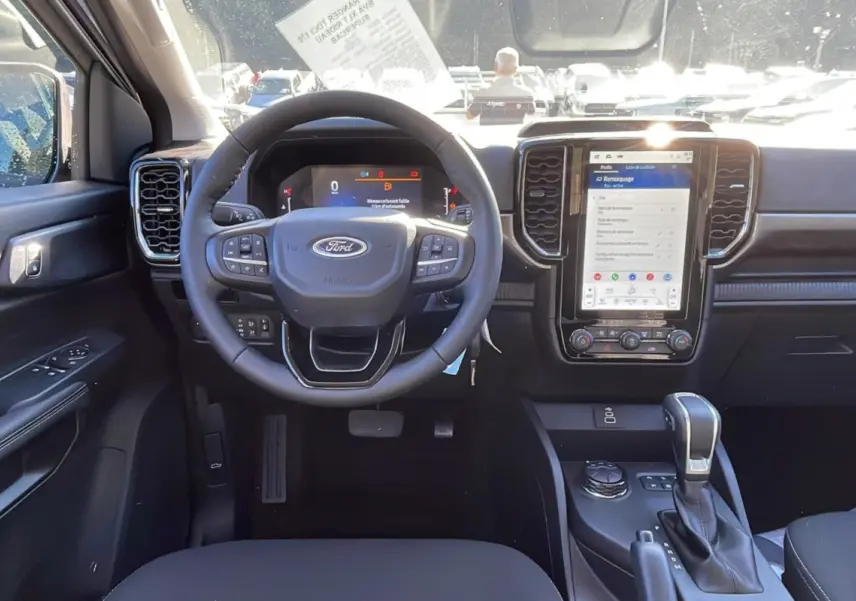 Vue intérieure frontale du tableau de bord du Ford Ranger gris, avec volant multifonctions et écran tactile vertical.