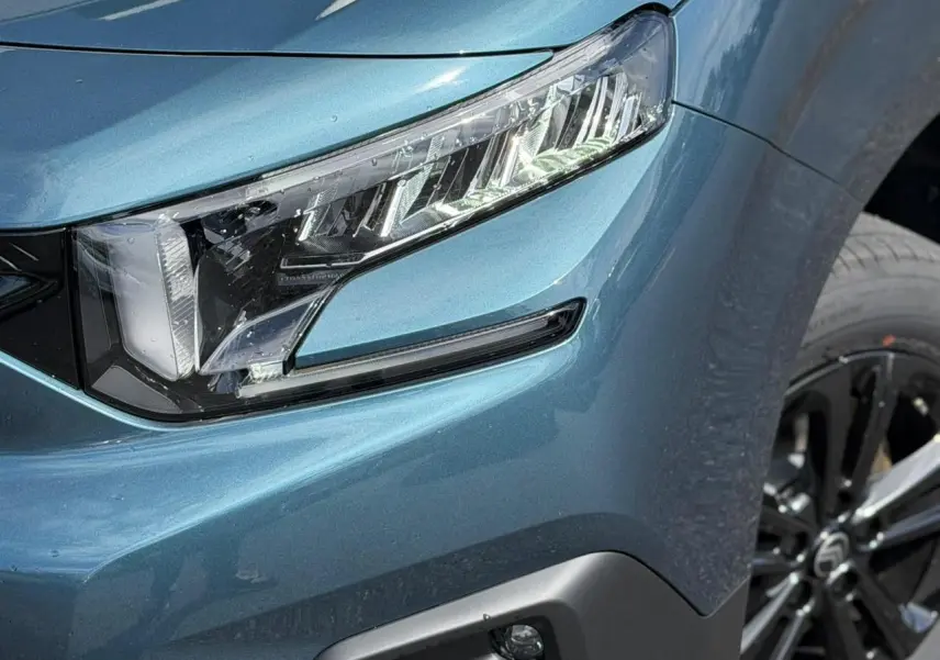 Gros plan sur le phare avant droit et la jante alliage noire du Citroën Berlingo Multispace Bleu Kiama 2026.