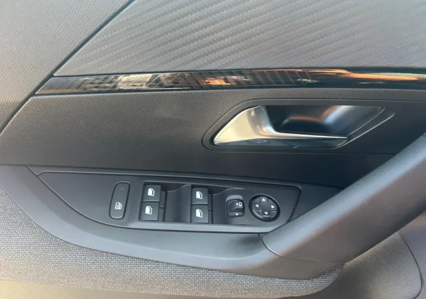 Gros plan sur la commande des vitres et rétroviseurs côté conducteur d’un Peugeot 2008 gris, version Hybrid 145 Style.