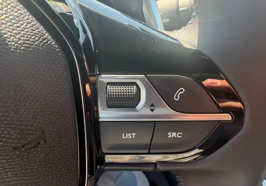 Gros plan sur les commandes multimédia au volant du Peugeot 2008 Hybrid 145 gris, avec molette et boutons d’appel.