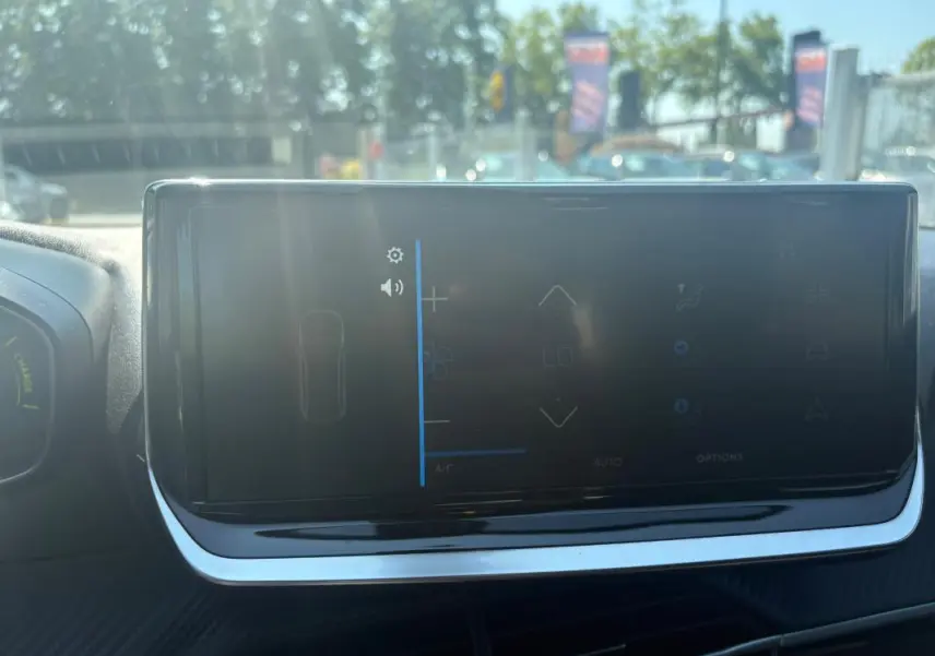 Écran tactile du tableau de bord du Peugeot 2008 Hybrid 145 gris, vue frontale intérieure avec reflet extérieur.