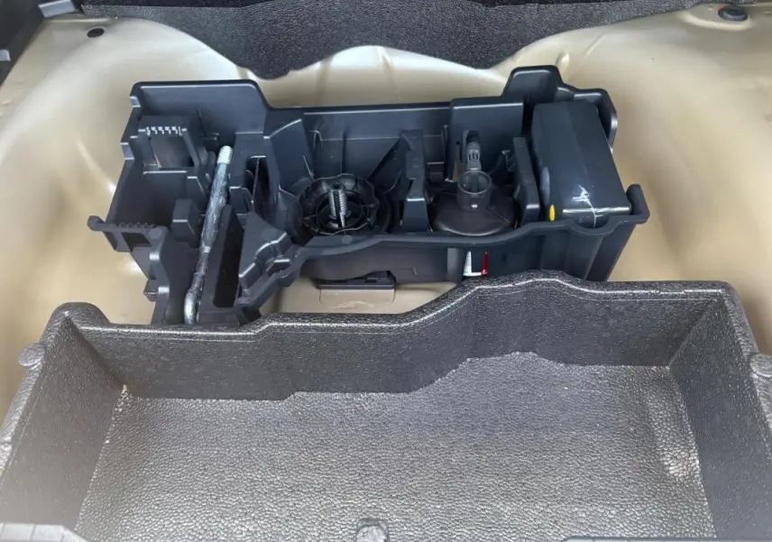 Vue rapprochée de l'espace de rangement gris sous le plancher du coffre du Peugeot 2008 Hybrid 145 e-DCS6 Style 2025.