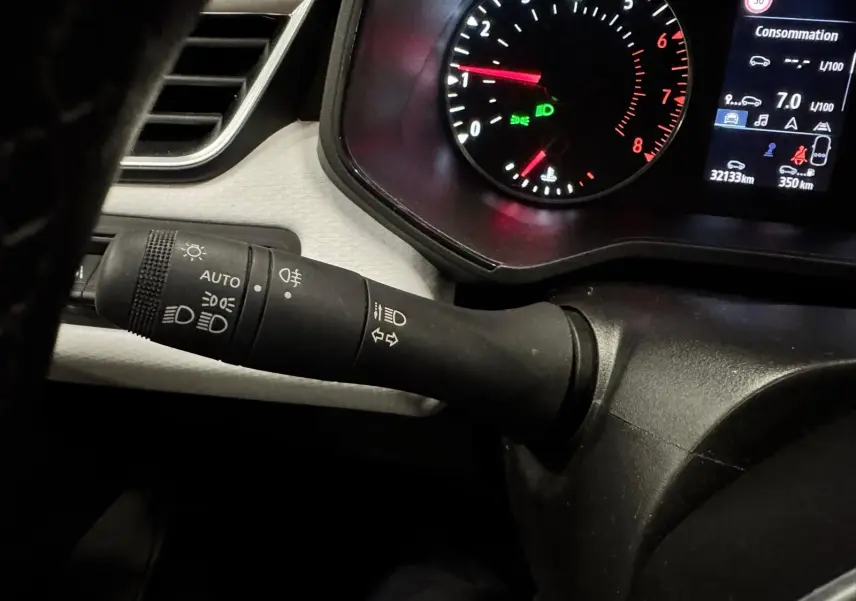 Gros plan sur la manette de phares et clignotants à gauche du tableau de bord gris noir d'une Renault Clio V 2022.