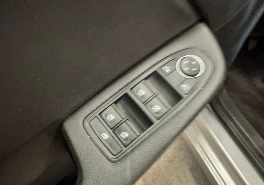 Panneau de commandes des vitres électriques et réglage des rétroviseurs côté conducteur d’une Renault Clio V gris aluminium.