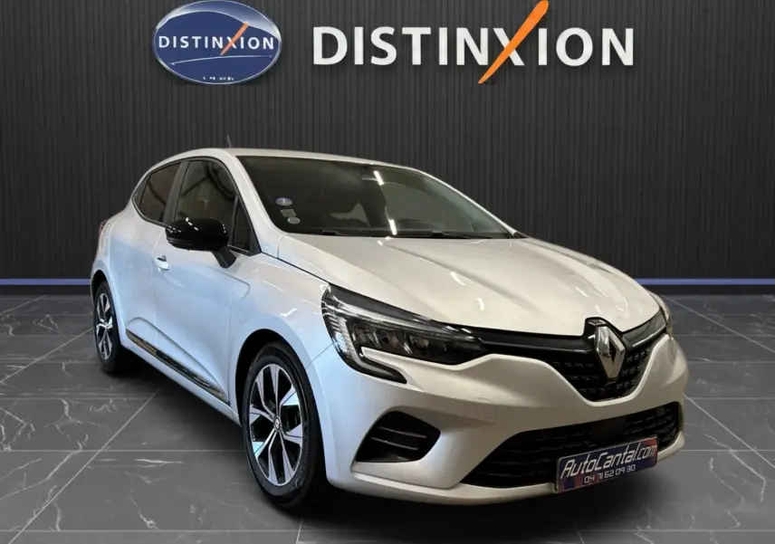 Vue 3/4 avant d'une Renault Clio V gris aluminium avec jantes biton et rétroviseurs noirs dans un showroom.