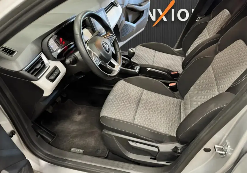 Vue intérieure côté conducteur de la Renault Clio V 1.0 SCE 65 CH Evolution avec sièges gris et volant multifonction.