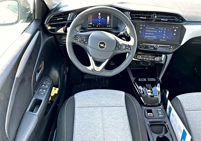 Vue intérieure avant de l'Opel Corsa 1.2 turbo 2025, volant multifonction, écran tactile et sièges tissu gris clair.