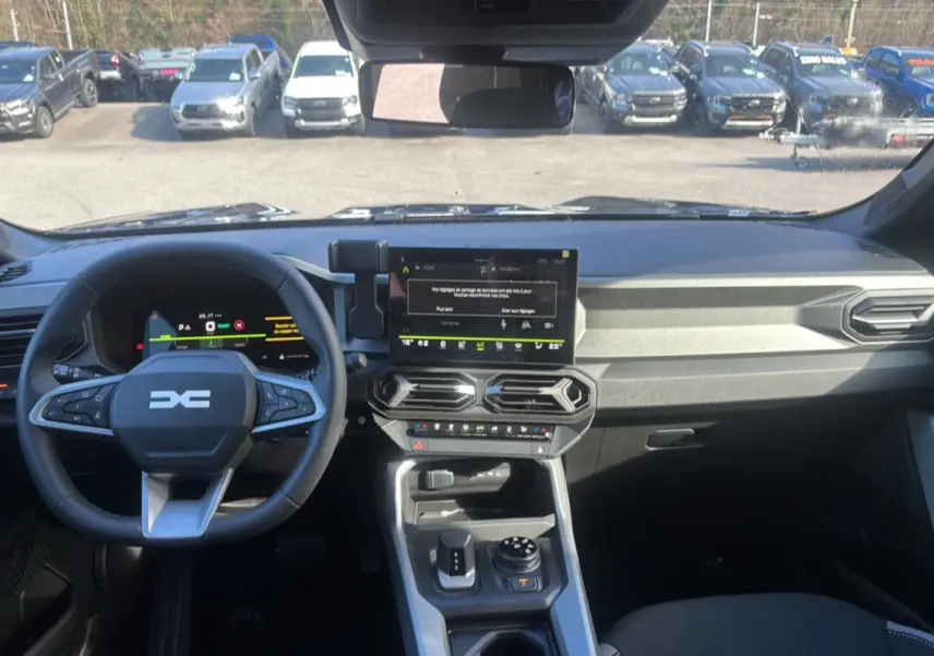 Vue intérieure avant du tableau de bord gris et volant cuir du Dacia Bigster Hybrid 150 4x4 Journey City 2026.