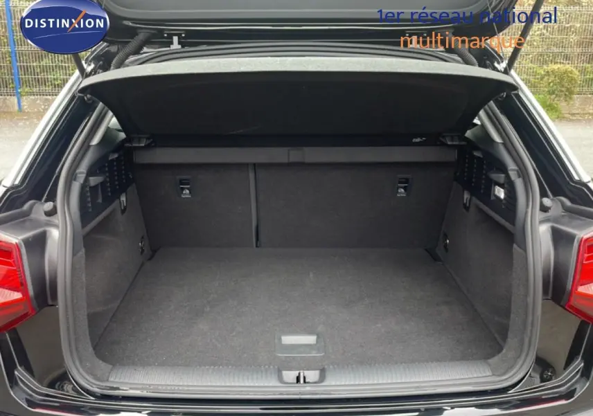 Coffre ouvert vu de l'arrière d'un Audi Q2 noir mito metal, montrant l'espace de chargement vide et propre.