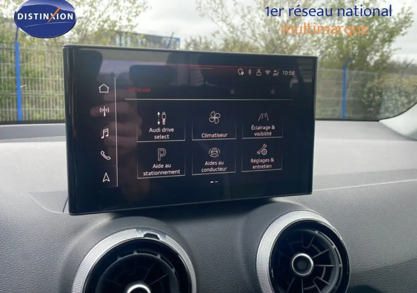 Écran tactile central affichant les options du véhicule dans l’habitacle d’un Audi Q2 noir mito metal, vue intérieure frontale.