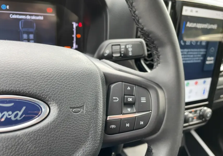 Gros plan sur le volant multifonctions en cuir du Ford Ranger 2025 avec écran tactile et commandes au volant visibles.