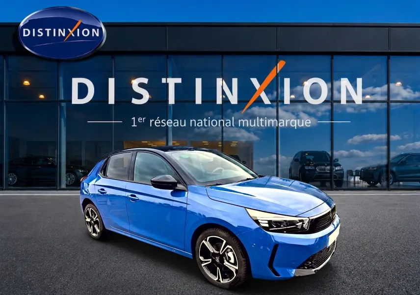 Opel Corsa 1.2 turbo bleu en 3/4 avant droit, avec jantes alu et phares LED devant un showroom Distinxion.