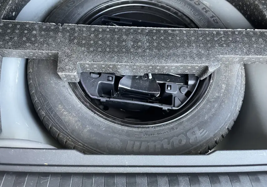 Gros plan sur la roue de secours noire logée dans le coffre d'un Peugeot 2008 gris 2019.