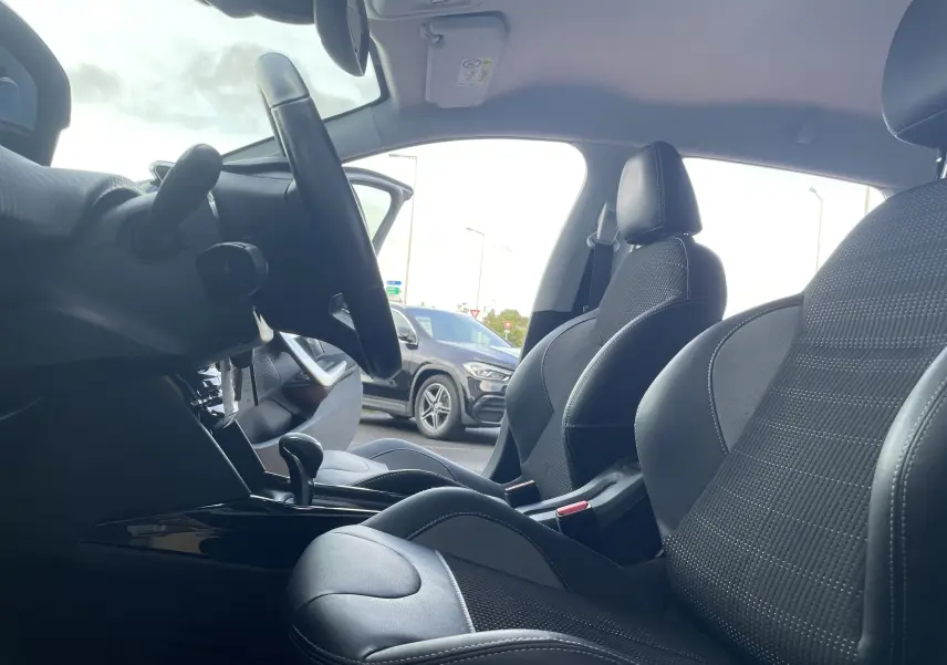 Vue intérieure côté conducteur du Peugeot 2008 2019 avec sièges mixtes cuir et tissu noirs et volant visible.