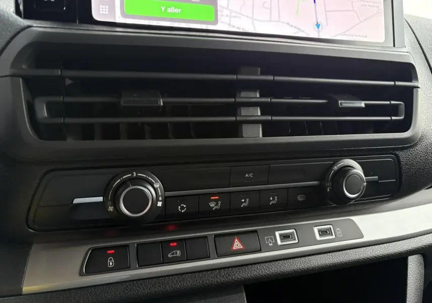 Gros plan sur la console centrale du Peugeot Expert Fourgon blanc, montrant les commandes de climatisation et les ports USB.