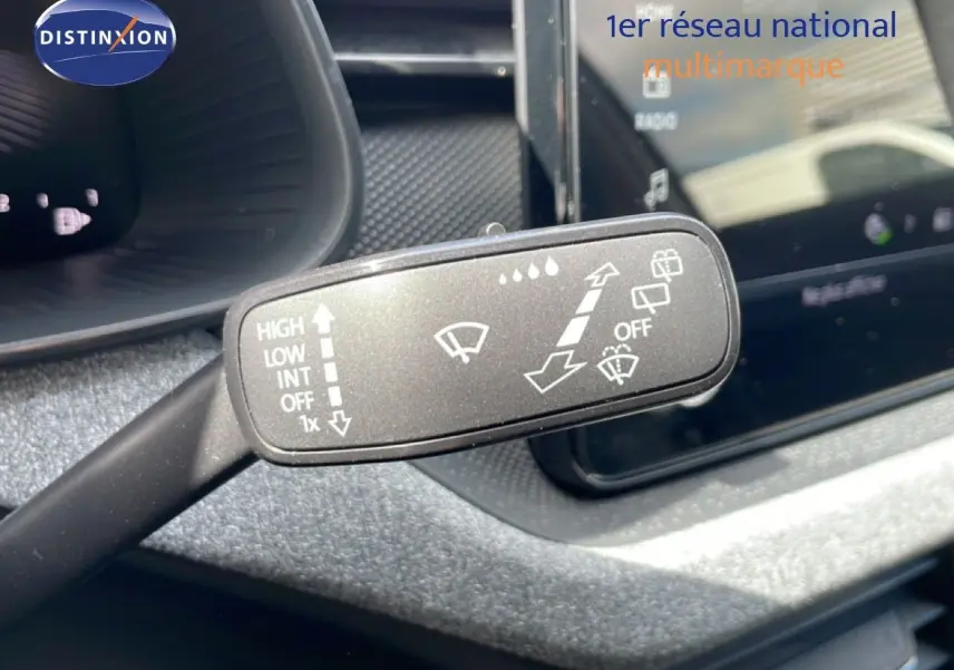 Gros plan sur la commande d’essuie-glace dans l’habitacle d’une Skoda Scala blanc glacier, avec tableau de bord et écran tactile en arrière-plan.