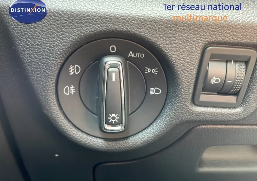 Gros plan sur la molette de réglage des phares du Skoda Scala blanc glacier, intérieur noir texturé.