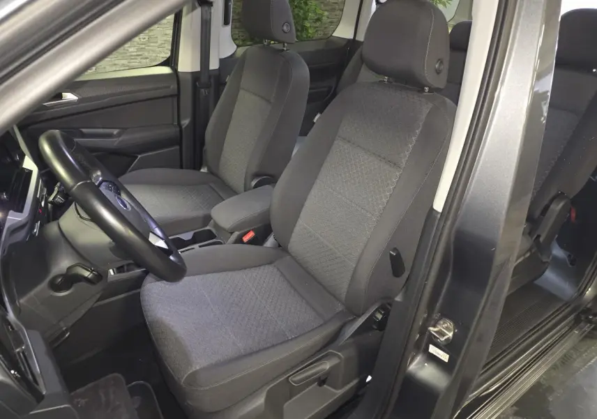 Vue intérieure côté conducteur du Ford Transit Connect gris 2023, montrant les sièges avant en tissu gris.
