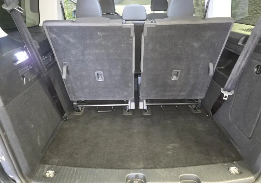 Vue arrière du coffre du Ford Transit Connect gris 2023 avec sièges arrière rabattus et tapis noir.