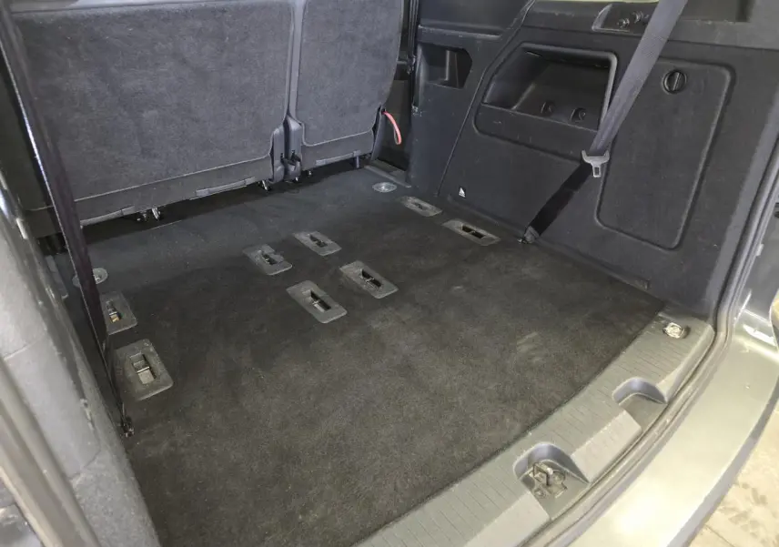 Vue intérieure arrière du coffre noir du Ford Transit Connect Tourneo Connect 2023 avec sièges rabattus et ceinture de sécurité visible.