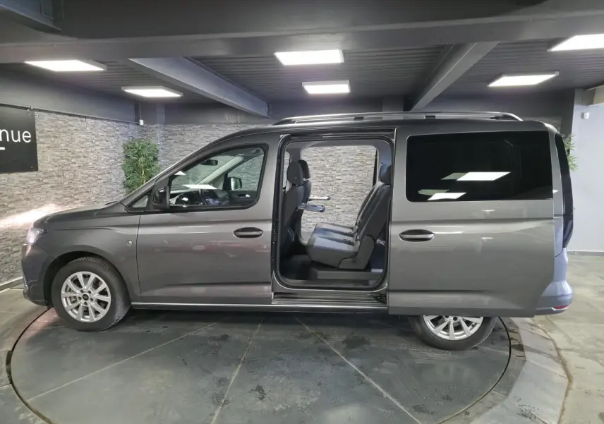 Vue de profil droit du Ford Transit Connect gris métallisé avec porte coulissante arrière ouverte montrant les sièges 7 places.