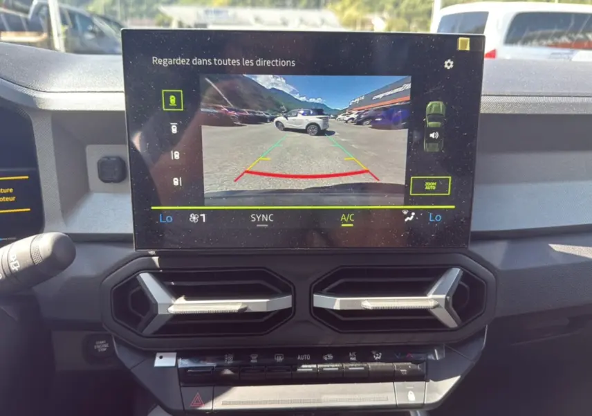 Vue intérieure du tableau de bord du Dacia Bigster Hybrid 150 avec écran multimédia affichant la caméra multiview.