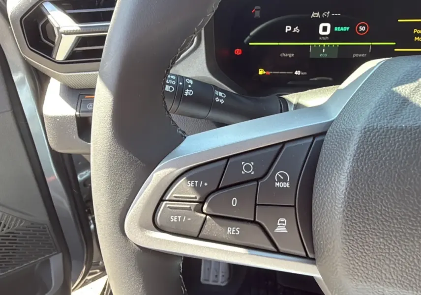 Gros plan sur le volant cuir côté gauche du Dacia Bigster gris schiste, avec commandes de régulateur et tableau de bord digital.