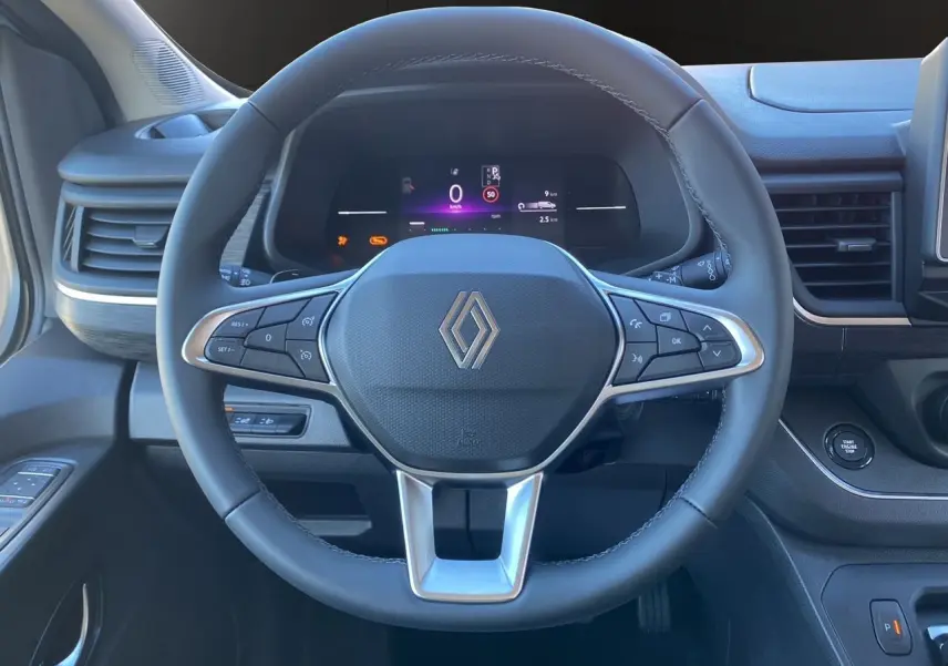 Volant noir en cuir avec logo Renault au centre, tableau de bord digital et bouton start/stop dans un Renault Trafic Combi 2025.