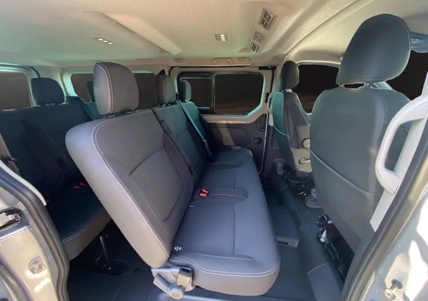 Vue intérieure côté droit du Renault Trafic Combi 2025, sièges tissu noir et porte coulissante ouverte.