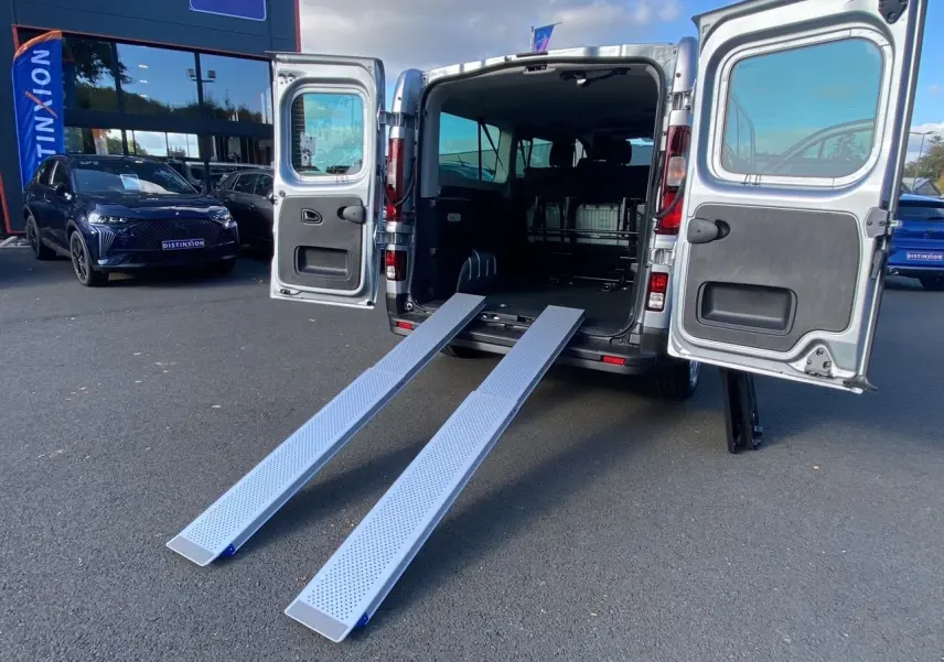 Vue arrière du Renault Trafic Combi gris Highland 2025 avec portes ouvertes et rampes d'accès déployées.