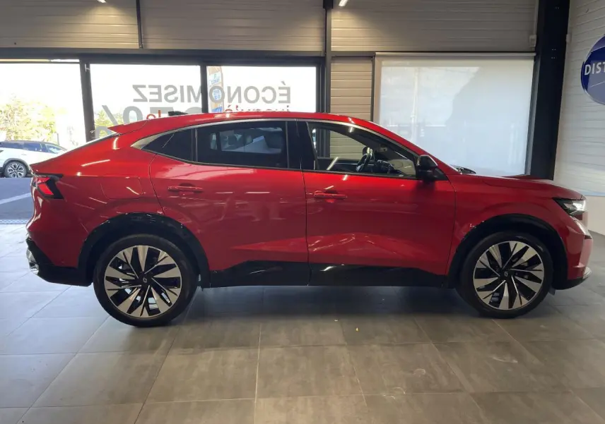 Profil côté gauche du Renault Rafale 2025 rouge avec toit noir et jantes alliage diamantées noires en showroom.