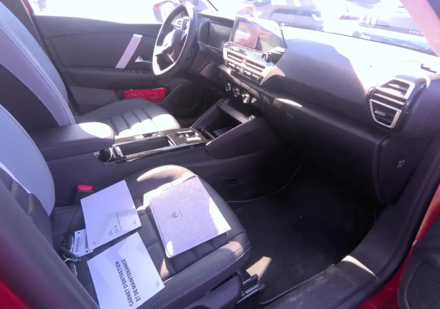 Intérieur avant droit du Citroën C4 Hybrid 2025, sièges gris, tableau de bord noir avec écran tactile central.