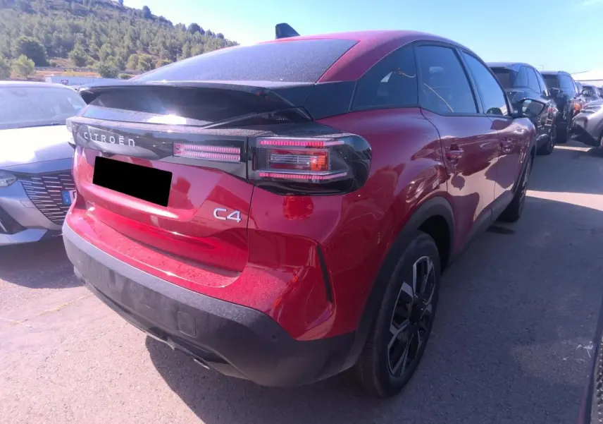 Vue 3/4 arrière droite d'une Citroën C4 hybride rouge Elixir avec toit noir et feux arrière LED distinctifs.