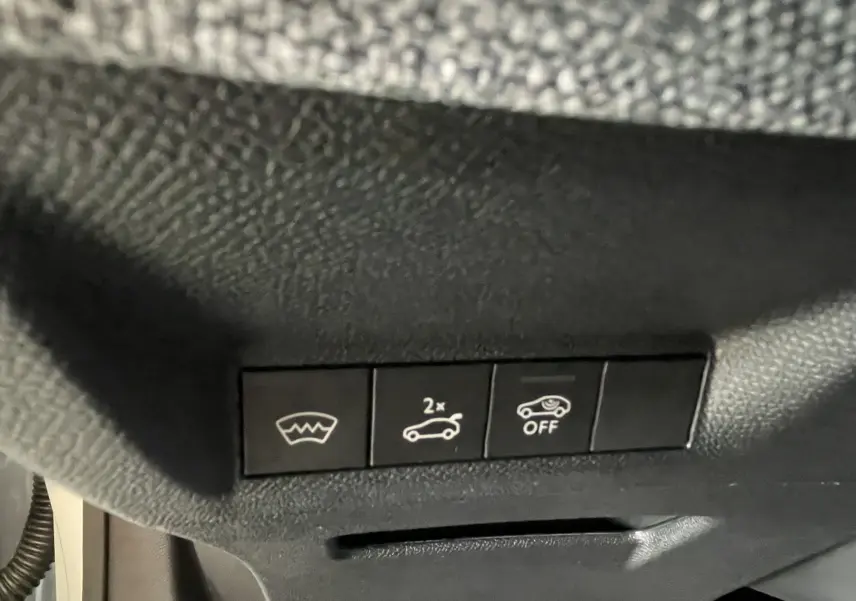 Gros plan sur les boutons de commande du hayon et pare-brise chauffant dans un Peugeot 3008 blanc Okenite.