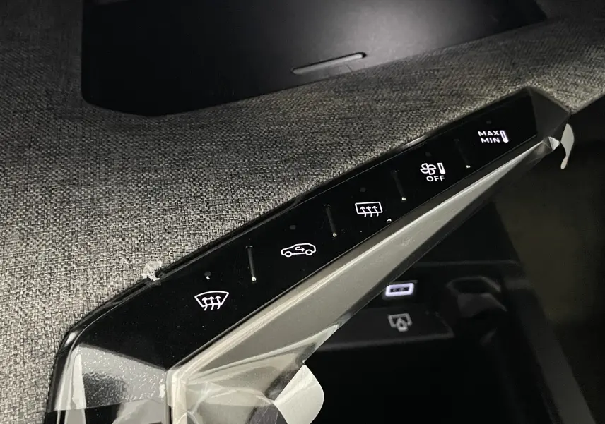 Gros plan sur la console centrale tactile du Peugeot 3008 Hybrid 2026 avec commandes climatisation et désembuage.