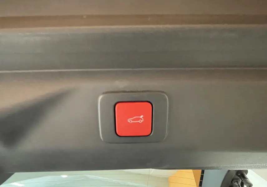 Bouton rouge de fermeture électrique du hayon visible à l'intérieur du coffre du Peugeot 3008 Hybrid blanc.