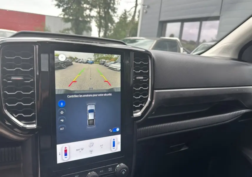 Vue intérieure du tableau de bord du Ford Ranger 2025 avec écran tactile affichant la caméra de recul et les commandes climatisation.