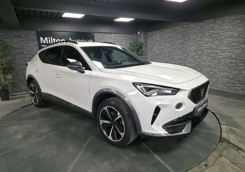 Vue 3/4 avant d'un CUPRA Formentor blanc avec jantes alliage noires et détails contrastants Dark Alu dans un showroom.