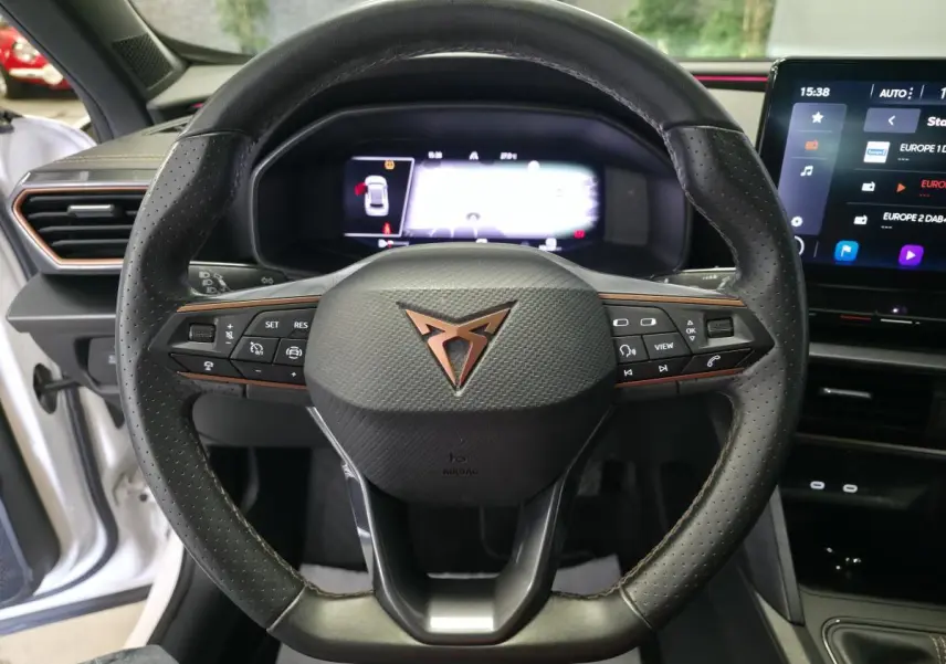 Vue rapprochée du volant sport en cuir noir avec logo CUPRA cuivré, tableau de bord digital et écran tactile du Formentor blanc 2024.