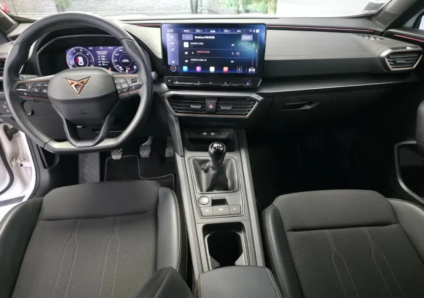Intérieur avant du CUPRA Formentor blanc 2024, vue du tableau de bord avec volant cuir, écran tactile et boîte manuelle.