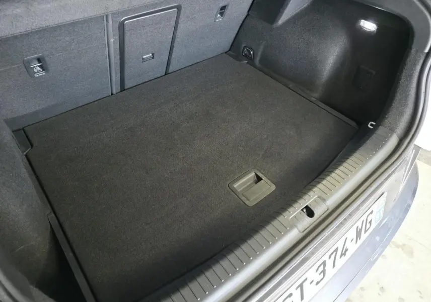 Coffre ouvert du CUPRA Formentor blanc, vue plongeante montrant le plancher plat et les finitions intérieures noires.