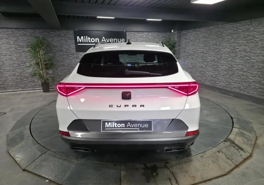 Vue arrière d'un CUPRA Formentor blanc avec bandeau lumineux LED rouge et double sortie d'échappement noire.
