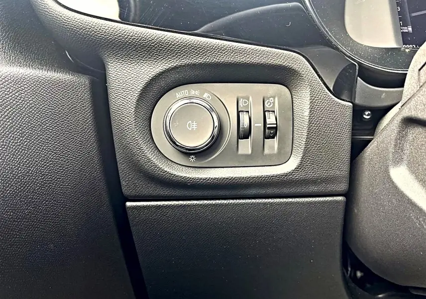 Gros plan sur les commandes d’éclairage noires à gauche du volant dans l’habitacle de l’Opel Corsa bleu 2025.