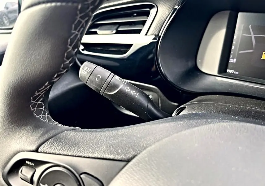 Gros plan sur la manette de clignotant et le volant noir avec surpiqûres blanches de l'Opel Corsa 1.2 turbo 2025.