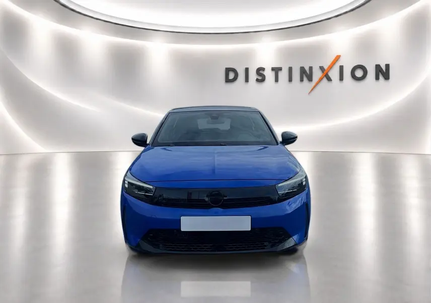 Vue frontale d'une Opel Corsa 1.2 turbo 100 gs bleu, avec calandre noire et éclairage LED, sur fond lumineux "Distinxion".